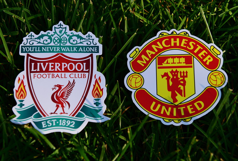liverpool fc and manchester united fc badges on grass rivalry